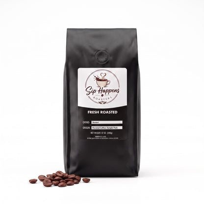Black bag of Sip Happens Roasters Fresh Roasted coffee beans with a few scattered coffee beans on the surface in front, set against a plain white background.